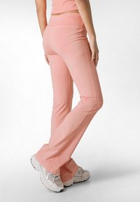 Flared roze yoga pants van zachte stof met een gladde textuur, voorzien van een brede tailleband en contrasterende stiksels.