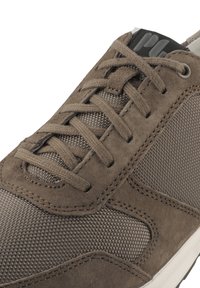 Sneaker in suede marrone con pannello in tessuto testurizzato, lacci sottili e un tallone nero a contrasto con dettagli del logo.