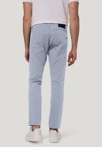 Lichtblauwe katoenen chinos met een slim fit, voorzien van twee achterzakken en riemlussen, gecombineerd met witte sneakers.
