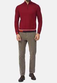 Maglione zip-up maroon con vita a righe; abbinato a pantaloni di velluto a coste marrone chiaro e scarpe marrone scuro.