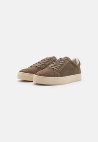 Brune semsket sneakers med lav profil, rund tå og beige gummisåle. Har flate lisser og polstret krage for komfort.