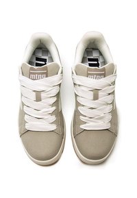 Sneakers beige con lacci bianchi, tomaia in tessuto liscio, colletto imbottito e logo vicino alla linguetta. Punta arrotondata e suola testurizzata.