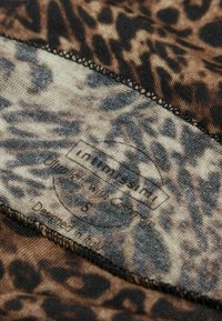 Leopardenmusterstoff mit weicher Textur. Verfügt über dunkle Brauntöne und Beige, genähte Kanten und ein Etikett mit der Aufschrift "Importiert aus Italien."