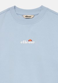 Sudadera de cuello redondo azul claro con pequeño logotipo blanco de "ellesse" y emblema en rojo naranja centrado en el pecho.