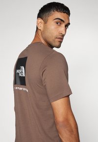 The North Face M SS BOX NSE TEE - T-shirts print - smokey brown/black