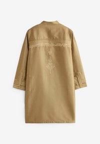 Vêtement traditionnel beige à manches longues en tissu texturé, avec motifs brodés sur le haut du dos et les poignets, et sangles de manches boutonnées.