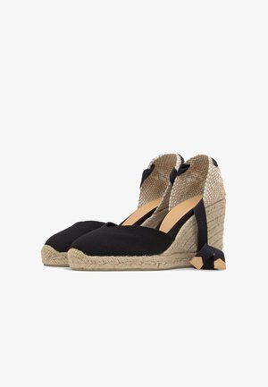 Espadrilles met sleehak met zwarte stoffen neus, gevlochten jutezool, geweven hielkapje en zwarte enkelbandjes.