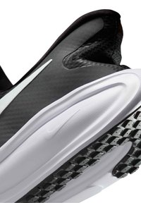 Gros plan d'une chaussure de sport noire et blanche montrant une semelle extérieure en caoutchouc texturée, une semelle intermédiaire amortie et une partie de la tige avec un logo Swoosh visible.