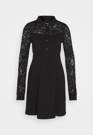 Vestido negro con cuello tipo camisa, mangas largas de encaje, fila de botones y cuerpo texturizado. El encaje presenta patrones florales.