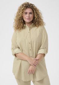 Gestreiftes Langarm-Hemd in hellem Beige mit Knopfleiste; verfügt über aufgerollte Ärmel und eine Brusttasche; weicher, strukturierter Stoff.