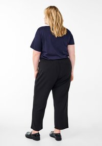 Schwarze, lockere Hose aus weichem Stoff, kombiniert mit einem dunkelblauen T-Shirt mit kurzen Ärmeln und entspannter Passform.