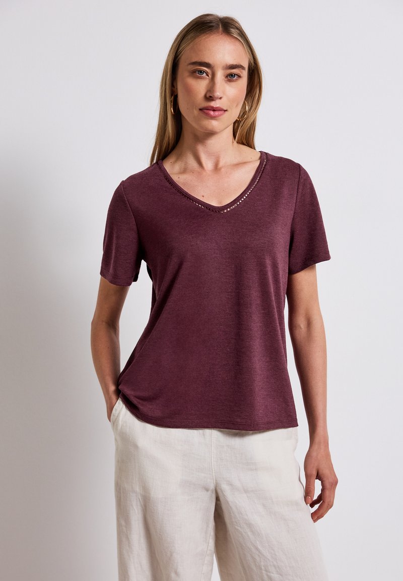 Camiseta de manga corta burdeos con cuello en V y costuras decorativas a lo largo del escote. Fabricada en una tela suave y ligera, de corte casual.