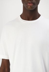 Witte katoenen t-shirt met een ronde hals en korte mouwen. De stof lijkt zacht, glad en lichtgewicht, met een simpel ontwerp.