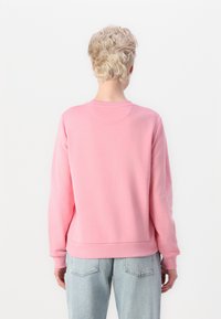 Pink sweatshirt with a round neckline, long sleeves, and ribbed cuffs. Soft, textured fabric with a fitted waistband.