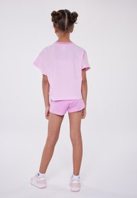 Camiseta de algodón rosa con mangas cortas y pantalones cortos a juego. Diseño simple, corte relajado, textura suave y sin patrones visibles.