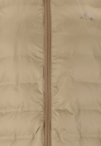 Beige polstret jakke med central lynlås og lille trekantet logo på den øverste højre side.
