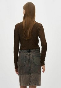 Braun strukturierter Langarmtop, kombiniert mit einem verwaschenen Jeans-Bleistiftrock mit Taschen auf der Rückseite und einer Nahtdetail entlang dem Saum.