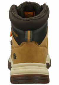 Stivale in suede marrone e pelle nera con colletto imbottito, dettagli gialli e suola in gomma testurizzata. Presenta un linguetta per l'estrazione e dettagli con logo.