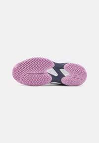 Lilla gummisåle med zigzag-mønster, formede sektioner i marineblå og hvid, designet til greb og ydeevne.