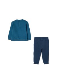 Sudadera azul con cuello redondo y detalle de botón en la parte trasera, combinada con pantalones de chándal azul oscuro ajustados con cintura elástica.