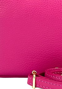 Fuchsia leren handtas met een textuur op de oppervlakte en een goudkleurig hardware accent. Inclusief een bijpassende gerolde schouderband.