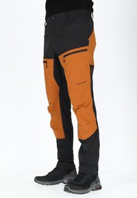 Trekkingbyxor i svart och orange, med dragkedjefickor, elastisk midja och ett hållbart, vattenavvisande material.