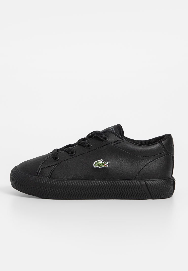 Czarne skórzane sneakersy z fakturowaną gumową podeszwą, pięcioma otworami na sznurówki oraz zielonym haftowanym logo krokodyla po boku.