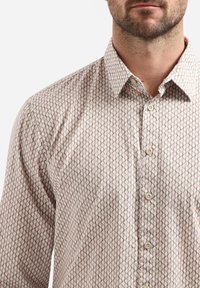 Geprinte overhemden in lichtbeige met een geometrisch ontwerp in groen en roze, met een klassieke kraag en plastic knopen.