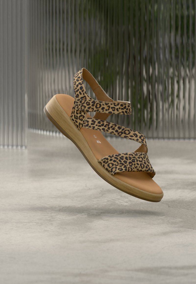 Sandal med leopardmønster og flere kryssende stropper, naturfarget såle og lav trehæl. Elegant design med teksturert stoffoverflate.