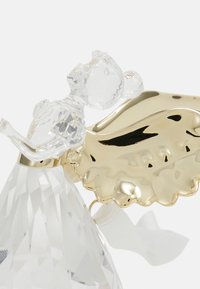 Figurina in vetro trasparente di un angelo con accenti dorati, caratterizzata da una base a flutti e un design delle ali liscio. Decorata con un nastro intrecciato.