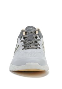 Grijze sportieve schoen met mesh-stof, vetersluiting en subtiele gele accenten. Rond neu en gemarmerde zool voor grip.