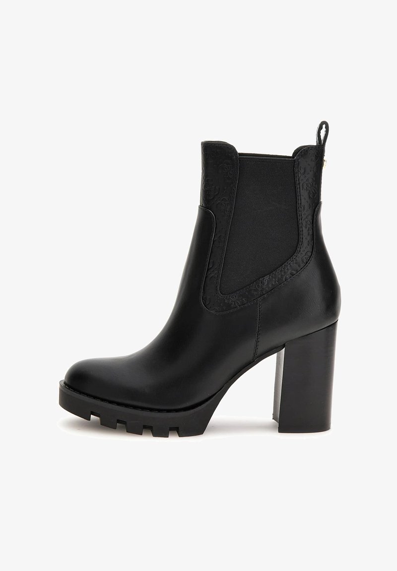 Stivale ankle in pelle nera con tacco alto chunky, suola a carrarmato, pannello elastico laterale e dettaglio in rilievo attorno alla caviglia e al tab di impugnatura.