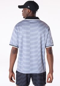 Grijze korte mouw polo met een herhalend "SAN ANTONIO" tekstpatroon. Zwarte kraag- en mouwaccenten. Gladde stoftextuur.