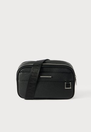 Schwarze rechteckige Umhängetasche aus strukturiertem Material, ausgestattet mit einem Reißverschluss und einem verstellbaren Tragegurt mit geprägtem Logo.