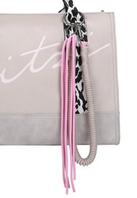 Canvas tote bag in light grey, featuring a pink logo, black and white patterned strap, and textured pink and beige tassels.