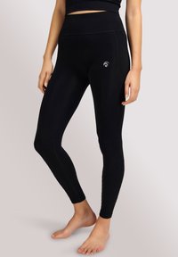 Zwarte leggings gemaakt van rekbare stof, met een hoge tailleband, een strakke pasvorm en een klein logo-accent aan de zijkant.