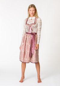 Spitzenbluse mit hohem Kragen, Ripsbandakzenten und floralem Rock in Pink mit gestickten Details; Taillenkordel aus Satin. Minimalistischer Hintergrund.