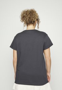 Tamsiai pilkas medvilnės marškinėliai su trumpomis rankovėmis, apvaliu kaklu ir laisvu siluetu, pasižymi lygiu paviršiumi ir neturi matomų raštų ar akcentų.