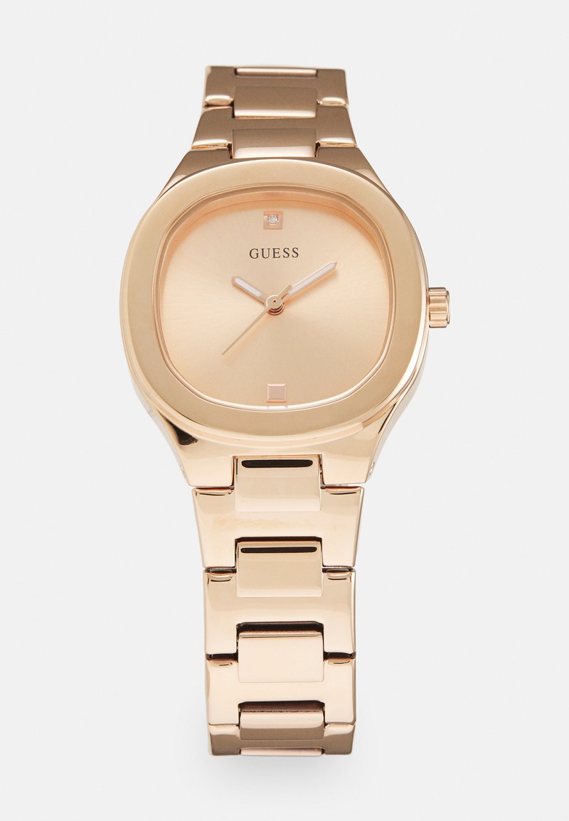 Montre en or rose avec un cadran carré arrondi, un cadran minimaliste et un bracelet en métal poli composé de maillons rectangulaires. Petite pierre d'accent à 12 heures.