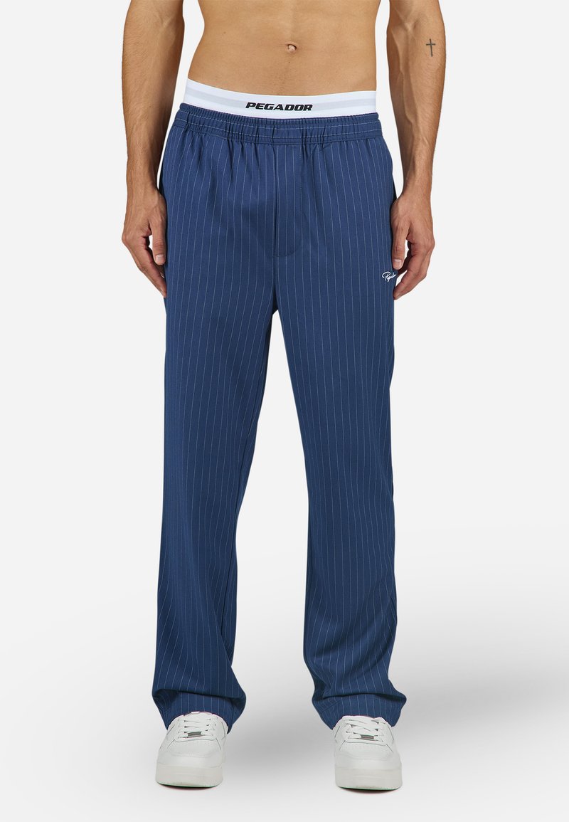 Blauwe broek met streepjes en een elastische tailleband met een wit logo. Gemaakt van zachte stof en op maat gemaakt voor een relaxte pasvorm.