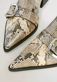 Sko med snakeskin-mønster og spids tå i mat finish, med en sølvspænde på et brunt bånd og en lav sort hæl.