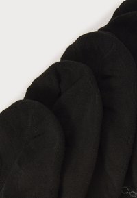 Ein Set aus vier schwarzen Knöchelsocken, gestapelt auf einem weißen Hintergrund, das den Zehenbereich und die Stoffstruktur hervorhebt.