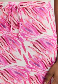 Rosa und weiße gemusterte Rock aus einem weichen, strukturierten Stoff, mit einem Kordelzugbund und abstraktem Pinselstrichdesign.