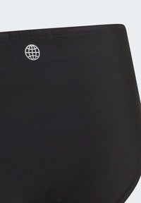 Slip da bagno nero realizzato in tessuto morbido, caratterizzato da un delicato motivo testurizzato e un piccolo logo argentato sul cinturino.