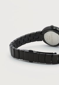 Μαύρο ρολόι χειρός Calvin Klein με μεταλλικό μπρασελέ από κρίκους, ορατό κούμπωμα και πίσω μέρος από ανοξείδωτο ατσάλι με χαραγμένα το λογότυπο της μάρκας και λεπτομέρειες αντοχής στο νερό.
