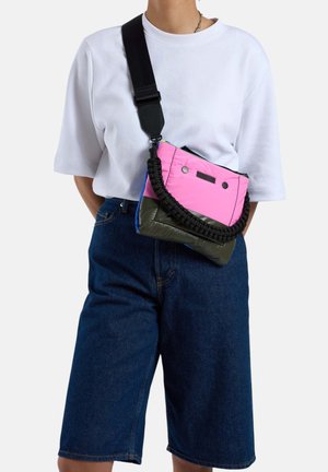 Sacoche en nylon colorée avec des sections rose et vert olive, une poignée tressée et une fermeture éclair dotée de deux boutons accentués.