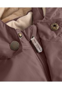 Burgunderrote, wasserdichte Jacke mit einem weichen cremefarbenen Futter, ausgestattet mit Metallknöpfen, einem Reißverschluss und einem Markenetikett im Kragen.