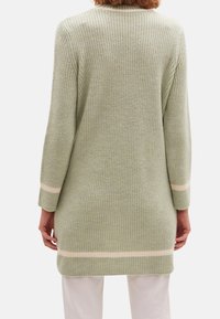 Cardigan lungo a coste di colore verde chiaro con strisce color crema chiaro ai polsini e all'orlo. Presenta una vestibilità comoda e un materiale in maglia testurizzata.