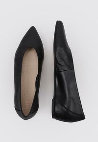 Bailarinas de cuero negro con punta afilada, diseño elegante, textura suave y suela baja y flexible. El interior presenta un sutil grabado de la marca.