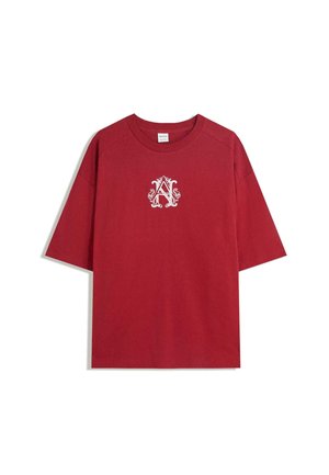 Tricou roșu cu mânecă scurtă, din bumbac, având un logo alb ornat cu litera "A" în centru. Textură netedă, cu un design lejer.
